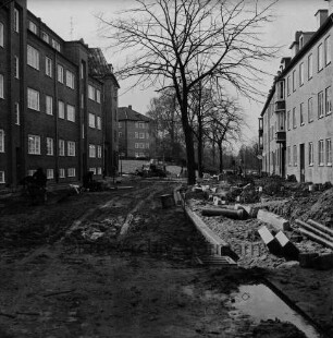 Mewesstraße: Blick Richtung Kurparkallee: vorn Baumaterial und Arbeiter: hinten Mitte an Einmündung Reimer-Hansen-Straße Bagger: dahinter Kurparkhügel mit Bäumen und Kreishaus