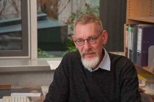 Porträt Perk Loesch, Fachreferent der SLUB : Porträt des Kunstwissenschaftlers Perk Loesch, Fachreferent und von 1996 bis 2019 Leiter der Handschriftenabteilung an der Sächsischen Landesbibliothek – Staats- und Universitätsbibliothek Dresden (SLUB). Aufnahme an seinem Schreibtisch