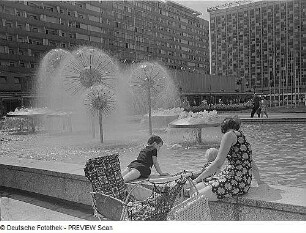 Wasserspiel mit Pusteblumen (Kugelbrunnen) : Dresden. Sich ausruhende Mutter mit zwei Kindern und Kinderwagen am Brunnenrand der Wasserspiele "Pusteblumen"