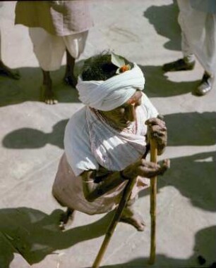 Stehender, auf zwei Stöcke gestützter Bettler : Varanasi (Indien). Stehender, auf zwei Stöcke gestützter Bettler
