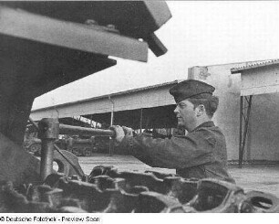 Goldberg (Kreis Lübz). Nationale Volksarmee - Landstreitkräfte. Panzerregiment 8 (PR-8). Freifläche vor Panzerhallen. Soldat bei Instandsetzungs- bzw. Wartungsarbeiten an Gleisketten für Kampfpanzer T-54