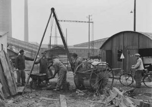 Industrie-Kraftwerk. Entschlammen der Kanalisation (?). Arbeiter mit Dreibock-Seilwinde an einem Kanalschacht : Lauta (Niederlausitz). Industrie-Kraftwerk. Entschlammen der Kanalisation (?). Arbeiter mit Dreibock-Seilwinde an einem Kanalschacht