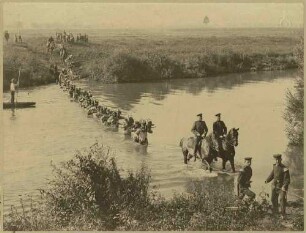 Feldübung: Karl Tuttmann, Oberleutnant in Begleitung von vier Offizieren zu Pferd, Soldaten marschieren durch einen Fluss, im Hintergrund zuschauende Kinder