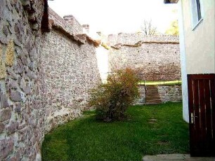 Kirchhof im Nordnordosten mit Kirchhofmauer im Verlauf nach Osten (mit Konsolsteinen und Steinbrüstung des Wehrgangs)