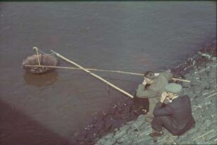 Deutschland. Zwei Männer beim Fischen (?) mit einem Regenschirm