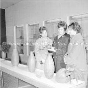 Besucher der Ausstellung zum Kunsthandwerk in der DDR betrachten Vasen und Gefäße