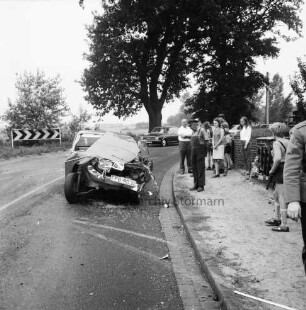 Verkehrsunfall: Unter den Eichen: Kollision eines Pkws mit einem Lkw: links Unfallwagen: rechts am Straßenrand Zuschauer: hinten links Warnschild an Kurve: hinten rechts weiterer Pkw Warnschild: dahinter Bäume und Wiesen