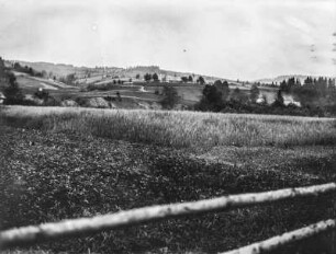 Am Feld : Blick über ein Feld auf ein Dorf