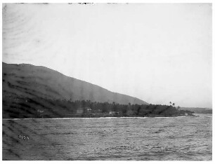 La Guajira (Kolumbien). Küstenlandschaft der Halbinsel mit Palmenhain und Ortschaft unterhalb eines Berges mit Festungsanlage