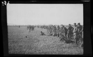 Bei Focșani (Rumänien): Soldaten neben aufgestellten Gewehren in lockerer Haltung auf einem weiten Feld (Distanzaufnahme) ("Kaiserparade")