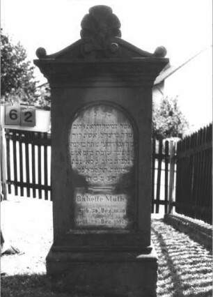 Grabstein 62 (Index: 100105119) Material: Sandstein Zustand: sehr gut Maße HxBxT: 159x68x31 cm Beschreibung: Stele, Sockel profiliert, Volutengiebel mit Verdachung, Mittelakroter, Schriftfeld eingetieft mit Rundbogenabschluß: Grabstein 62