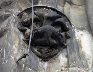 Maske neben einem Obergadenfenster
