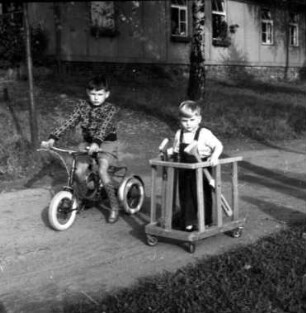 Hessisch-Lichtenau, Am Mühlenberg. Orthopädische Klinik. Zwei Jungen mit Dreirad und Spezialfahrzeug im Garten
