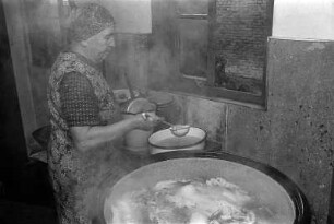 Die Bäuerin am Kessel kocht Fleisch aus
