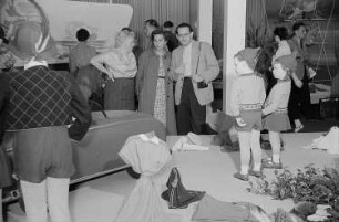 Mehrere Personen betrachten auf der Leipziger Herbstmesse 1955 ausgestellte Kindermode