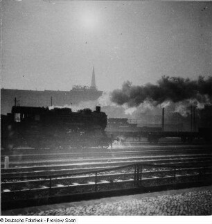 Güterzug-Lokomotive 56 434 der Deutschen Reichsbahn. Teilansicht (ohne Schlepptender) auf einer mehrgleisigen Bahnanlage. Gegenlichtaufnahme