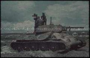 Deutsche Soldaten mit Filmkamera auf einem zerstörten sowjetischen Panzer