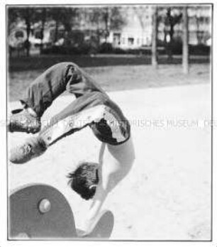 Junge macht auf einem Spielplatz einen Handstandüberschlag (Altersgruppe 18-21)
