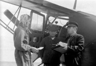 Pilot und zwei weitere Personen vor einem Flieger