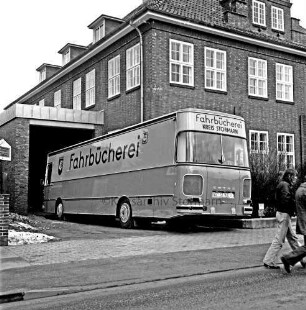 Bad Oldesloe: Bücherbus auf der Einfahrt in Anbau an gewerbliche Berufsschule: rechts im Bild 2 Fußgänger, im Vordergrund eine Straße
