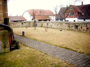 Kirchhof im Westen mit Kirchhofmauer sowie erhaltenen Schießscharten (Büchsen- oder Kreisscharten) in Brusthöhe (Wehrgang mit Brüstung abgetragen) in Übersicht