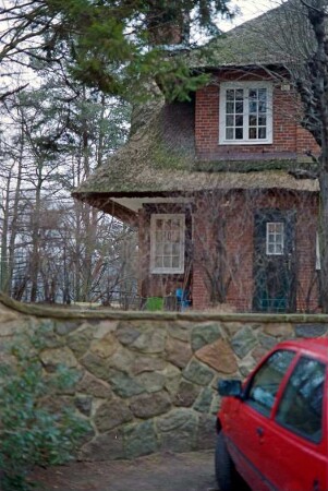 Pfefferberg: Landhaus aus Backstein mit Reetdach: Eingangsfront, Teilansicht: Gebäudeecke: Tür, Sprossenfenster, vorgezogenes Walmdach, Gaube: an Seitenfront Gaube mit Schornstein: im Vordergrund Feldsteinmauer