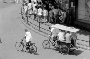 Straßenszene mit Passanten, Fahrrad- und Rikschafahrer