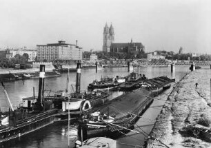 Magdeburg, Stadtansicht : Magdeburg. Elbe mit Radschleppdampfer, Frachtkähnen und Schwimmkran. Blick stromab zur Hubbrücke gegen den Dom und Elblagerhaus