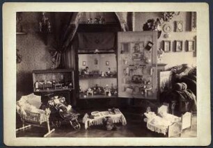 Weihnachten bei Prof. E. A. Donadini, Dresden : Ansicht eines Ausschnitts aus dem Wohnzimmer in der ersten Dresdner Wohnung des Malers E. A. Donadini mit Puppenhäusern, Puppenwagen und Puppenbetten