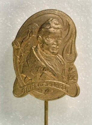Gabelsberger-Abzeichen (mit langer Nadel) : Medaillensammlung Stenografische Sammlung. Gabelsberger-Abzeichen (Brustbild Gabelsbergers, eingerahmt von Blattranken, darunter der Schriftzug "Gabelsberger", mit langer Nadel). Metall, vergoldet; Maße (ohne Nadel) 26 x 19 mm (um 1905). Dresden: SLUB R c 0378