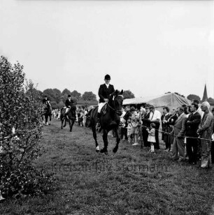 Sportveranstaltung: Pferdeleistungsschau: Turniergemeinschaft Stormarn-Süd mit Reit- und Fahrverein Trittau und Umgebung von 1922 e.V.: Ehrenrunde der Sieger-Reiterstaffel: dahinter Zuschauer