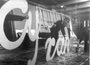 Berlin. Freie Berliner Volksbühne. Walter Minks begutachtet in der Schreinerwerkstatt des Theaters den für Reklamezwecke hergestellten Schriftzug "Cyrano"