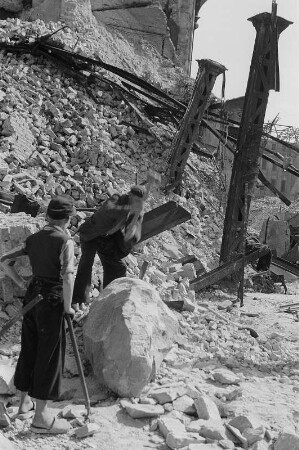 Berlin. Aufbauhelfer beim Zerkleinern von Trümmersteinen