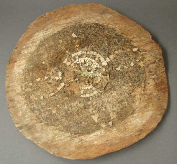 Round wooden panel with stone mosaic remnants