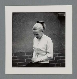 Blondes Mädchen, vor einer Hauswand sitzend, Berlin