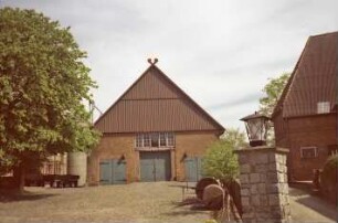 Fritz-Berodt-Straße 7-9: Hofanlage: östliches Wirtschaftsgebäude, Giebelseite mit Toren, darüber Fassadenplastiken, Inschrift, Fensterband, an Giebel Verbretterung, Giebelzier Pferdeköpfe: links Silo, westliches Wirtschaftsgebäude [verdeckt]: vorne Hofplatz mit Kopfsteinpflaster, Baum, Pfeiler von Hofeinfahrt: rechts Weg, Wirtschaftsgebäude [angeschnitten]