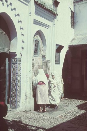 Reisefotos. Zwei Frauen und ein Mann an einem mosaikverzierten Wandbrunnen (vielleicht in Algier)