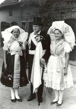 Hochzeitsbitter mit seiner Frau aus Kunersdorf : Kleidung - niedersorbische Tracht. Ort: Kósobuz / Kunersdorf. Hochzeitsbitter mit seiner Frau und ein Mädchen in der Kleidung für die Fastnacht und für das Hahnrupfen.