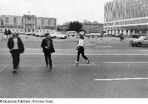 Die Fotografen Wolfgang Stricker und Christian Borchert überqueren die Straße, im Hintergrund das Staatsratsgebäude und das Ministerium für Auswärtige Angelegenheiten