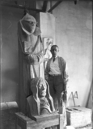 Magdeburger Ehrenmal : Güstrow, Schützenstraße 30. Atelier Ernst Barlachs. Der Bildhauer Bernhard A. Böhmer (Gehilfe Barlachs) mit der linken Gruppe des Magdeburger Ehrenmals. Eichenholz, geschnitzt (1929; E. Barlach)