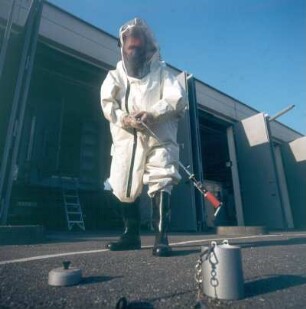 Karlsruhe. Kernforschungszentrum (heute: Forschungszentrum). Mitarbeiter der Technischen Gruppe im gasdichten Vollschutzanzug beseitigt mit Ferngreifer eine Strahlenquelle