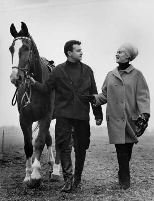 Freizeitsport Reiten. Ein Reiter führt ein Pferd am Halfter. Eine Frau spricht interressiert auf ihn ein