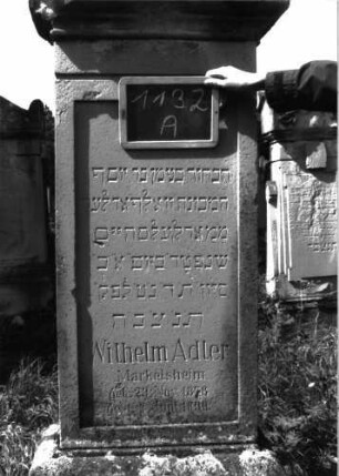 Grabstein 1132 (Index: 100104227) Material: Sandstein Zustand: gut erhalten, Sockel von Flechten bewachsen und verwittert Maße HxBxT: 170x53x20 cm Beschreibung: Stele auf getrepptem Sockel, Giebelaufsatz mit Eckakroterien, eingetieftes hochrechteckiges Schriftfeld, auf Sockel weitere Inschrift (?) Symbolik: Palmetten: Grabstein 1132A