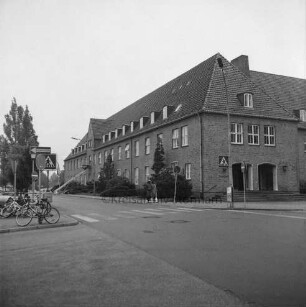 Altes Finanzamt [später Gebäude D]: Außenansicht: Blick von der Mommsenstraße: rechts Abzweigung Bangertstraße: links Fahrräder an Verkehrsschildern: in der Mitte zwei Fußgänger