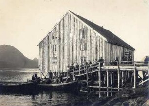 Digermulen auf Hinnöy/Lofoten. Touristen und Einheimische an der Landungsbrücke mit Ruderbooten gegen das Speicherhaus