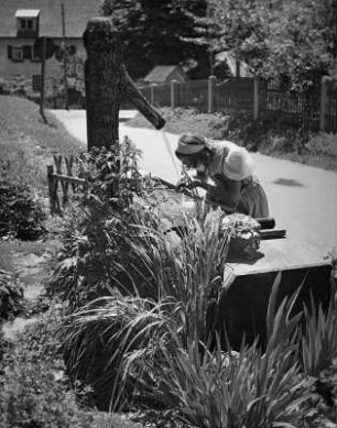 Junges Mädchen, an einer Gartenrabatte hockend