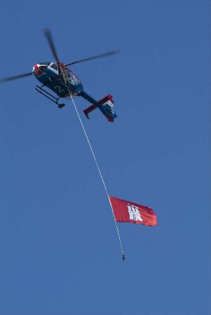 Der Hamburger Polizeihubschrauber 2 traegt an einem Seil die Hamburger Flagge, ueberfliegt die Elbe an den Landungsbruecken und eroeffnet somit den Hafengeburtstag. 05.2008