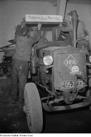 Traktoristen bringen ein Propaganda-Schild über dem Fahrerhaus eines Traktors an