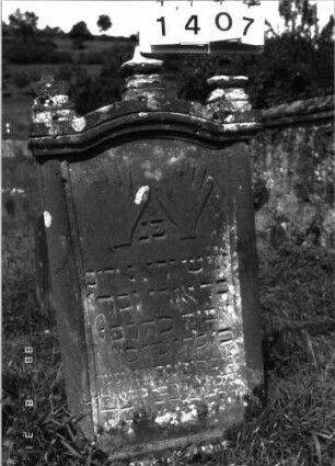 Grabstein 1407 (Index: 100098159) Maße HxBxT: 136x60x6 cm Symbolik: segnende Hände Besonderheit: kulturhistorisch wertvoll / hist.-wiss. Gründe (Gemeindestellung): Grabstein 1407