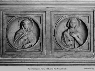 Marmorplatte mit Halbfiguren von Heiligen, wiederverwendet unter einer barocken Nischenfigur